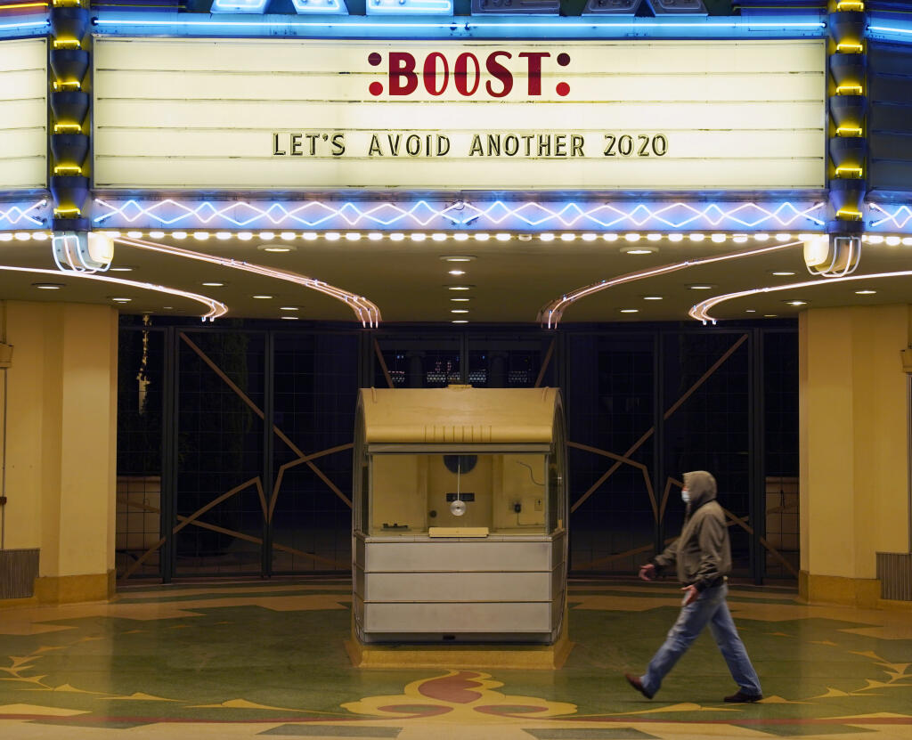 FILE - A man walks underneath the marquee of the Alex Theatre in Glendale, Calif., which bears a message urging people to get COVID-19 vaccine booster shots, Monday, Jan. 24, 2022.  The vaccination drive against COVID-19 in the U.S. is grinding to a halt, and lagging demand is especially stark in conservative corners of the country where many people weren't interested in the shots in the first place.(AP Photo/Chris Pizzello, File)