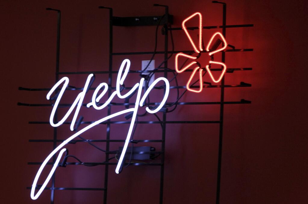 FILE - This Oct. 26, 2011, file photo shows the logo of the online reviews website Yelp in neon on a wall at the company's Manhattan offices in New York. A divided California Supreme Court has ruled that online review site Yelp.com cannot be ordered to remove posts against a San Francisco law firm that a judge determined were defamatory. The 4-3 ruling on Monday, July 2, 2018, came in a closely watched case that internet companies warned could be used to silence online speech. (AP Photo/Kathy Willens, File)