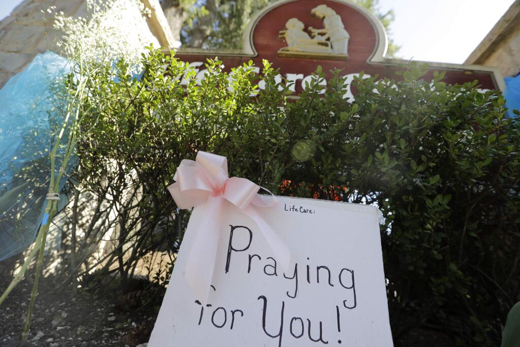 A handmade sign sits against the entry at Life Care Center Monday, March 16, 2020, in Kirkland, Wash., near Seattle. The facility has been the epicenter of the coronavirus outbreak in the state. (AP Photo/Elaine Thompson)