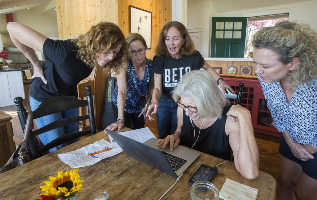 From left, at the Beto O'Rourke phone bank in Glen Ellen are volunteers Jane De Mordant, Patsy Wallace, Laura Stanfield, Ree Whitford and Gail Diserens. Ree is making the first call to a voter in Texas and everyone is gathered around to see how it goes. (Photo by Robbi Pengelly/Index-Tribune)