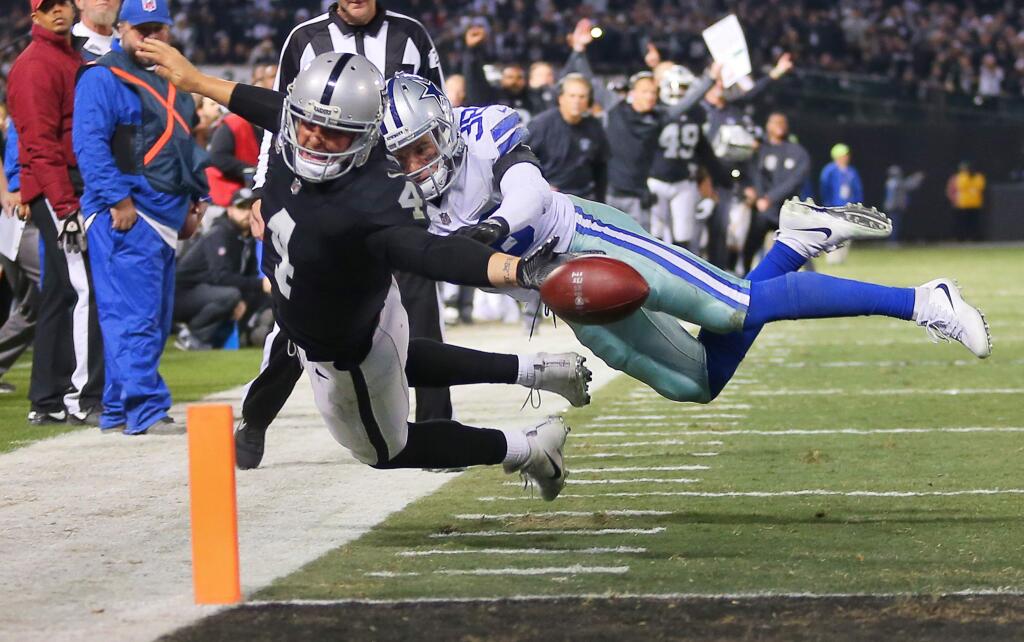 Oakland Raiders quarterback Derek Carr fumbles the ball out of the end zone for a touchback, while hit by Dallas Cowboys safety Jeff Heath, during their game in Oakland on Sunday, December 17, 2017. The Raiders lost to the Cowboys 20-17.(Christopher Chung/ The Press Democrat)