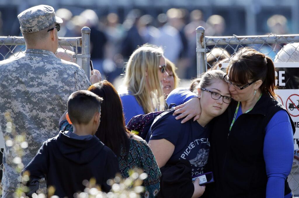 Parents and students walk away from an area at North Thurston High School Monday, April 27, 2015, where students were released to their parents after a shooting at the school earlier in the morning. Police say no one was injured, and school district officials say the gunman has been apprehended by staff. (AP Photo/Ted S. Warren)