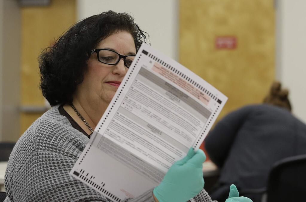 FILE - In this May 30, 2018, file photo, Beverly Darm, an election clerk at the Sacramento County Registrar of Voters, inspects a mail-in primary ballot, in Sacramento, Calif. Nearly 570,000 Californians have already voted in the November election, that's about 100,000 more than voted at this point in 2014. Monday, Oct. 22, 2018 is the last day to register to vote although people can register conditionally through Election Day. (AP Photo/Rich Pedroncelli, file)