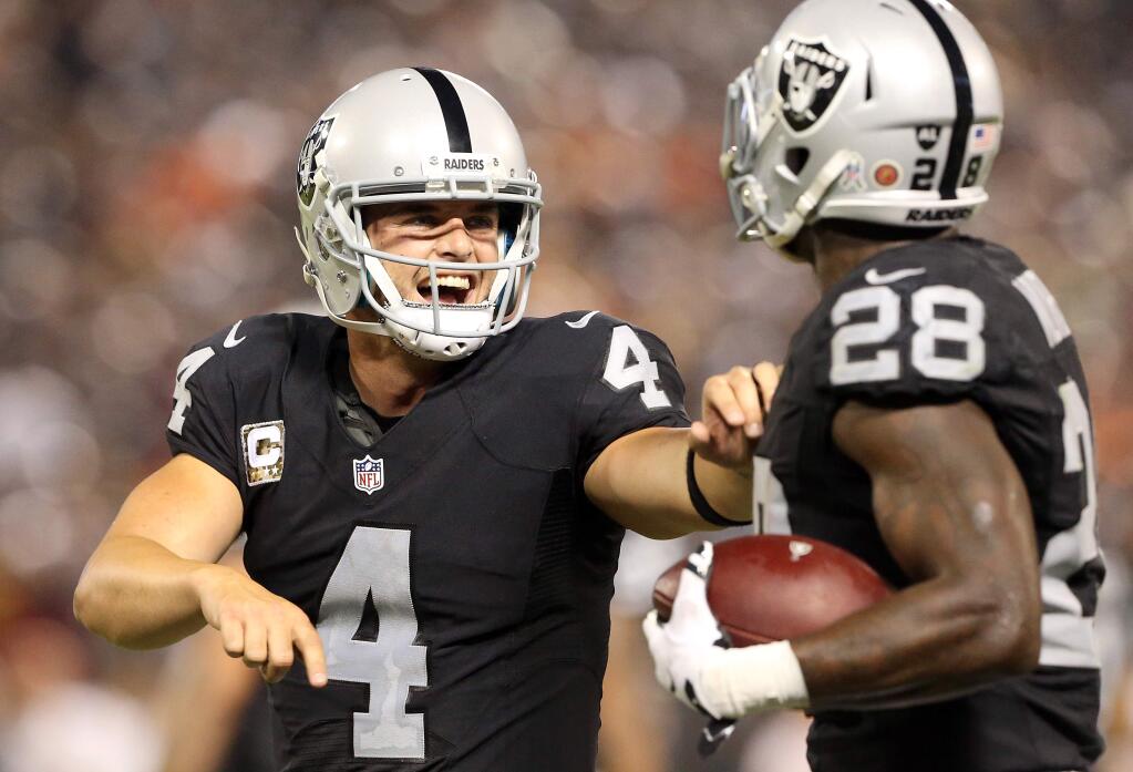 Oakland Raiders quarterback Derek Carr celebrates a touchdown with teammate Latavius Murray at the end of the second half during their game against the Denver Broncos in Oakland on Sunday, November 6, 2016. (Christopher Chung/ The Press Democrat)