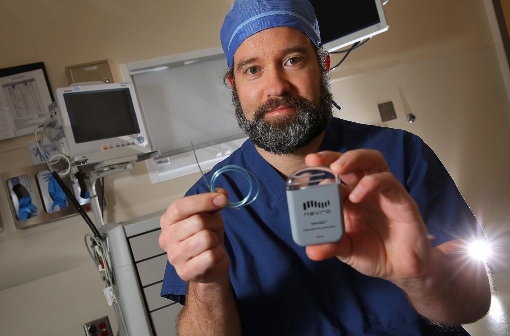 Dr. Jason E. Pope, president of Summit Pain Alliance, with an implant device that provides high frequency spinal cord stimulation that acts like 'a pacemaker for pain'.(Christopher Chung/ The Press Democrat)