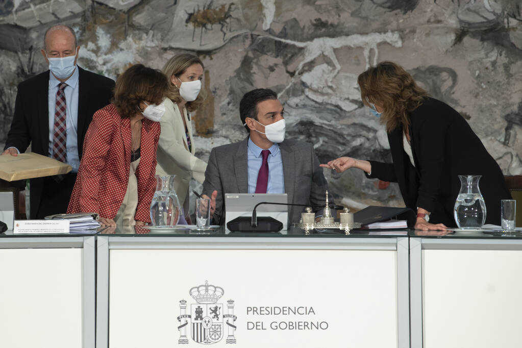 In this photo provided by the Spanish Government in Madrid, Spain's Prime Minister Pedro Sanchez, centre,  speaks with three of his ministers, during a cabinet meeting at the Moncloa Palace in Madrid, Tuesday June 22, 2021. The Spanish Cabinet met on Tuesday to issue pardons for nine imprisoned Catalans who spearheaded the 2017 effort to set an independent republic in the affluent northeastern region, a move that Prime Minister Pedro Sanchez says is needed to bring reconciliation. (Borja Puig de la Bellacasa/Spanish Government via AP)