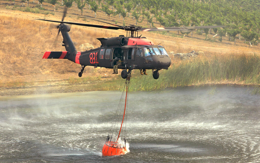An air National Guard helicopter dips out of a vineyard pond, Sunday, August 23, 2020 off Mill Creek Road in Healdsburg.  (Kent Porter / The Press Democrat) 2020