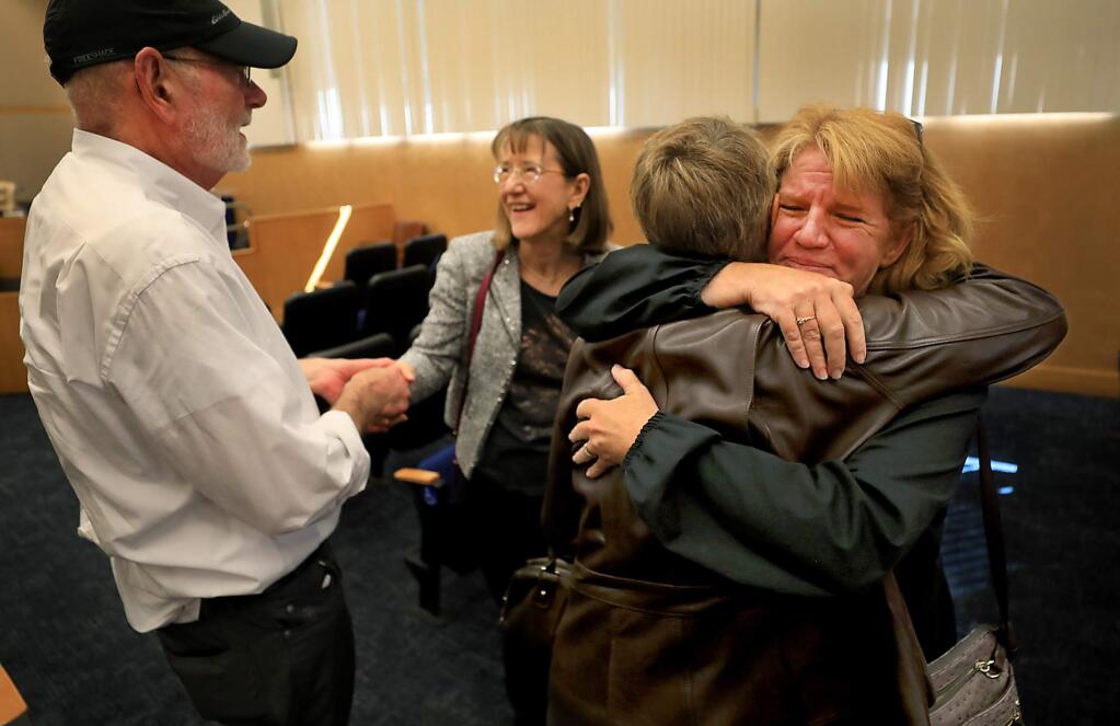 During a hearing on seismic testing for Wikiup residents who lost their homes in the Tubbs fire, Kim Davis fights back tears as she is comforted by friend and neighbor Lori Barber, as Michael Fargo congratulates his neighbor Jennifer Honey on a small victory at the Board of Supervisors, Tuesday Sept. 18, 2018 in Santa Rosa. Both Davis and Honey were burned out of their homes last October. Supervisors voted to streamline the issue surrounding seismic trenching and the associated cost which is delaying the rebuilding efforts for those on Wikiup hill. (Kent Porter / Press Democrat) 2018
