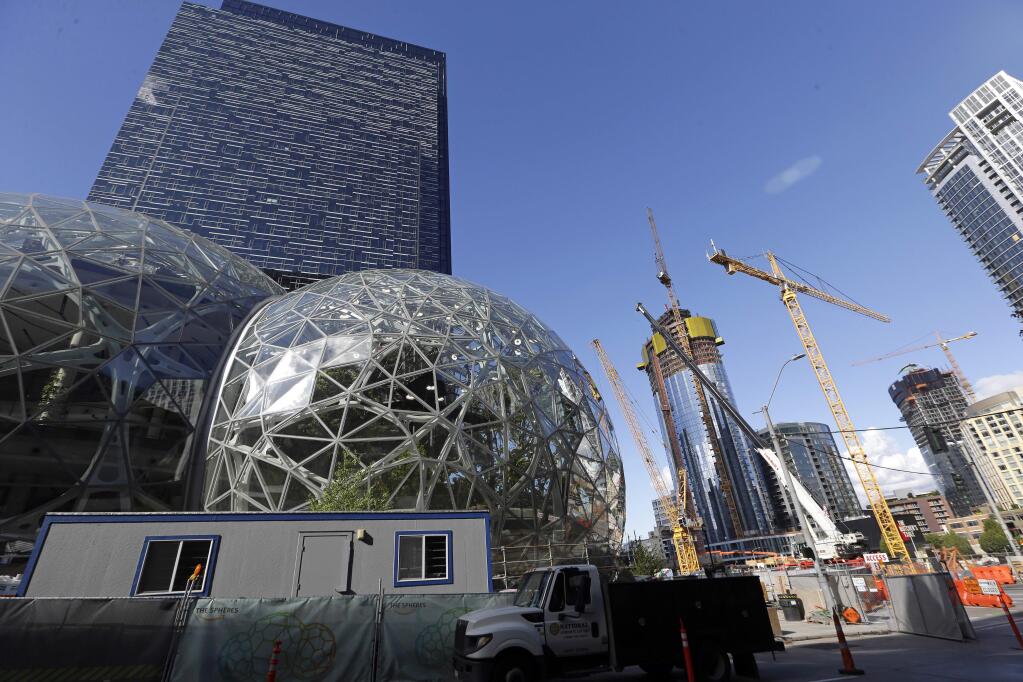 FILE - In this Wednesday, Oct. 11, 2017, file photo, large spheres take shape in front of an existing Amazon building, behind, as new construction continues across the street in Seattle. Amazon said Wednesday, May 2, 2018, it is pausing construction on a new high-rise building in Seattle while it awaits the outcome of a city proposal to tax worker hours. The Seattle City Council has been weighing a proposed 'head tax' on high-grossing businesses as a way to raise about $75 million a year for affordable housing and homelessness services. (AP Photo/Elaine Thompson, File)