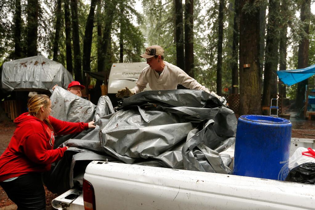 Mirabel Park residents Terry Naughton, left, David Miller, and Christina Campbell load a large tarp onto the back of Campbells pickup truck as they prepare to move their trailers to higher ground, at Mirabel Park in Forestville, California on Saturday, January 7, 2017. Residents living around the Russian River prepare for potential flooding, as the lower part of the river is currently expected to crest Monday afternoon at over 35 feet. (Alvin Jornada / The Press Democrat)