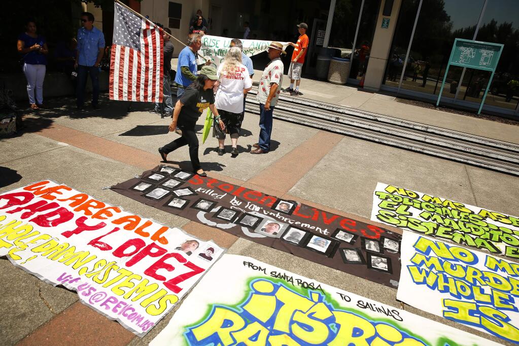 Demonstrators lay down signs protesting District Attorney Jill Ravitch's decision that no criminal charges will be filed against the Sonoma County Sheriff's deputy Erick Gelhaus who shot and killed 13-year-old Andy Lopez at the Sonoma County Superior Court in Santa Rosa on Tuesday, July 8, 2014. (Conner Jay/The Press Democrat)