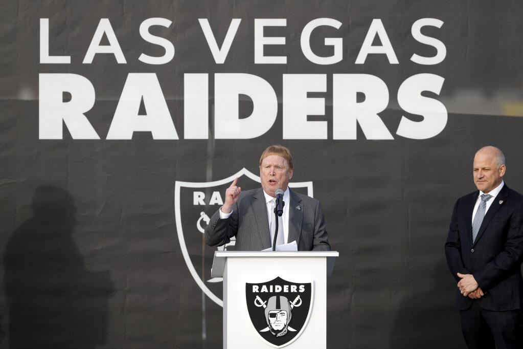 FILE - Las Vegas Raiders owner Mark Davis, center, speaks during a news conference, officially renaming the Oakland Raiders to the Las Vegas Raiders, in front of Allegiant Stadium in Las Vegas in this, Jan. 22, 2020, file photo. Raiders president Marc Badain listens at right. Mark Davis is expanding his sports empire in Las Vegas, buying the Aces from MGM Resorts International. The Raiders owner purchased the WNBA team Thursday, Jan. 14, 2021, pending approval from the league's board of governors.(Steve Marcus/Las Vegas Sun via AP, File)