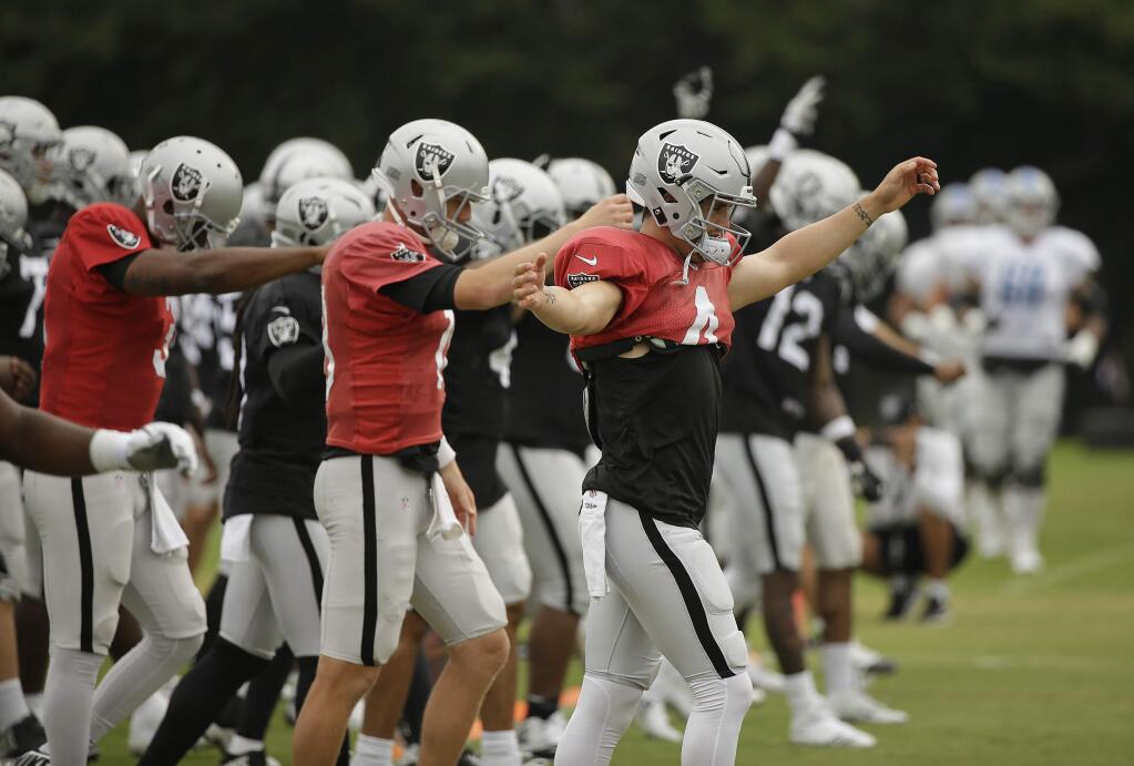 Oakland Raiders quarterback Derek Carr, right, warms up during practice Wednesday, Aug. 8, 2018, in Napa. (AP Photo/Eric Risberg)