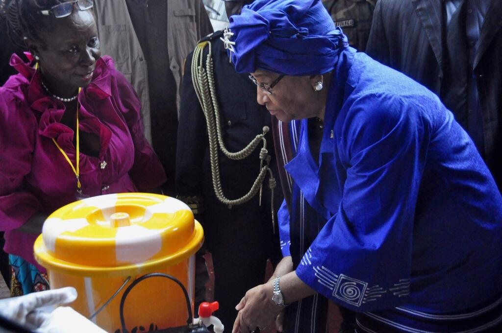 In this photo taken on Saturday, July 26, 2014, Liberia President Ellen Johnson Sirleaf, right, demonstrates to people how to wash their hands properly in order to prevent the spread of the Ebola virus, during Independence Day celebrations in the city of Monrovia, Liberia. Scientists from Fort Detrick say the number of Ebola cases in West Africa is much larger than official estimates indicate. Researchers from the U.S. Army Medical Research Institute of Infectious Diseases, who have worked in Sierra Leone and Liberia, say the current outbreak reaches beyond the 1,200 confirmed, suspected or probable cases and over 600 deaths that the World Health Organization has identified in West Africa as of July 23. (AP Photo/Abbas Dulleh)