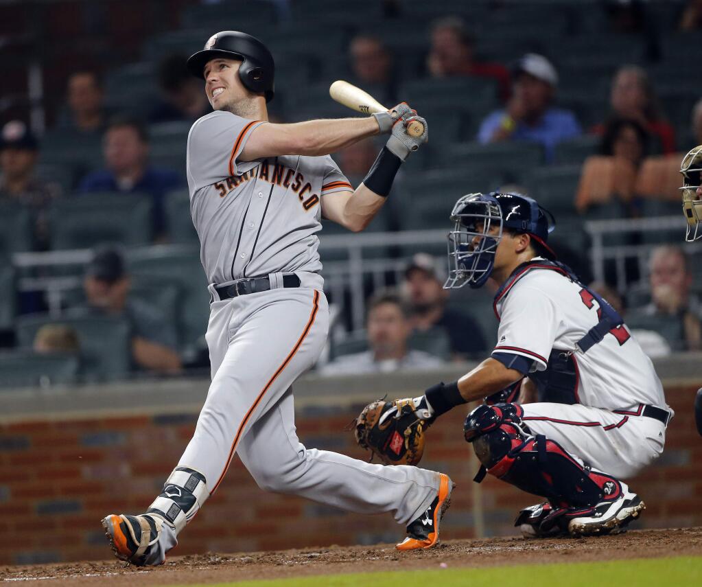 The San Francisco Giants' Buster Posey drives in a run with a double in the third inning, as Atlanta Braves catcher Kurt Suzuki watches Thursday, June 22, 2017, in Atlanta. (AP Photo/John Bazemore)