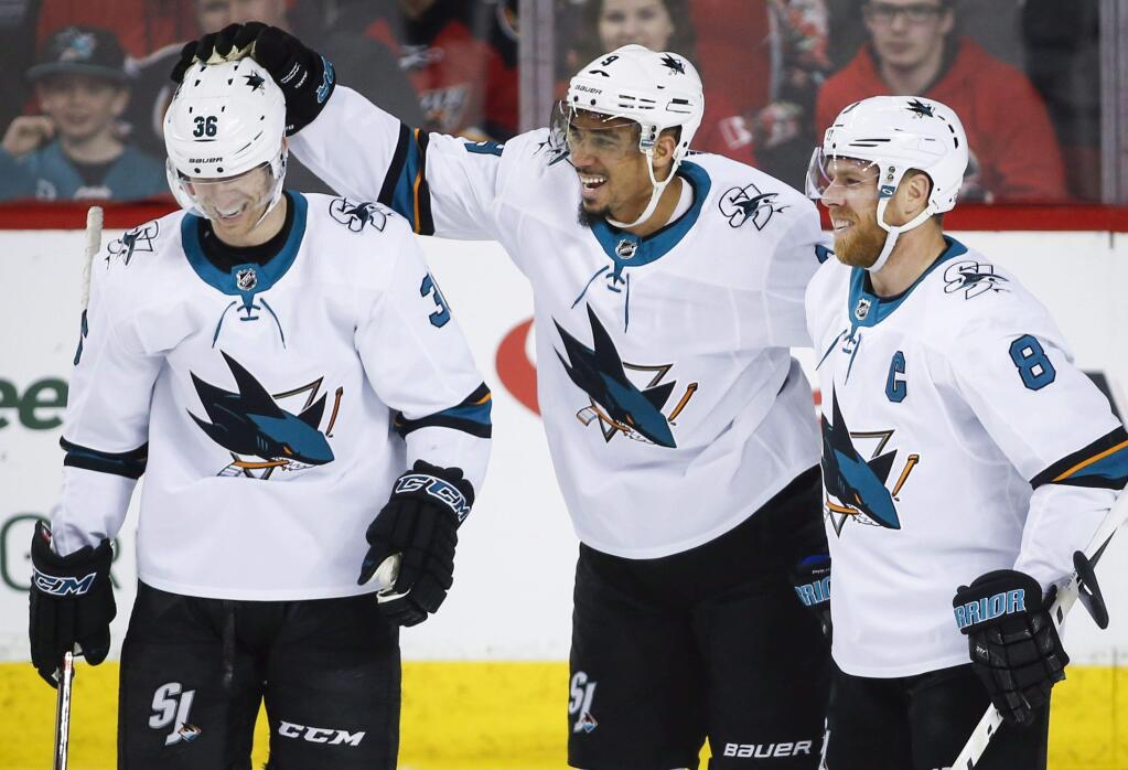San Jose Sharks left wing Evander Kane, center, celebrates his goal with right wing Jannik Hansen, left, and center Joe Pavelski during the first period against the Calgary Flames in Calgary, Alberta, Friday, March 16, 2018. (Jeff McIntosh/The Canadian Press via AP)