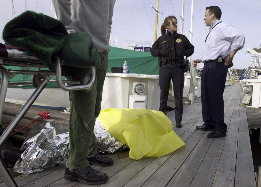 In this Feb. 28, 2004, photo, Sausalito police officer B. Baraz, back left, and then-Coroner Investigator Darrell Harris, right, prepare to move a body found at the yacht harbor in Sausalito, Calif. Harris has been arrested and charged with sexually abusing a girl younger than 14. He is scheduled to be arraigned Monday, May 8, 2107, on four felony charges and a misdemeanor count of sexually abusing the girl over the last nine years. (Jeff Vendsel/Marin Independent Journal via AP)