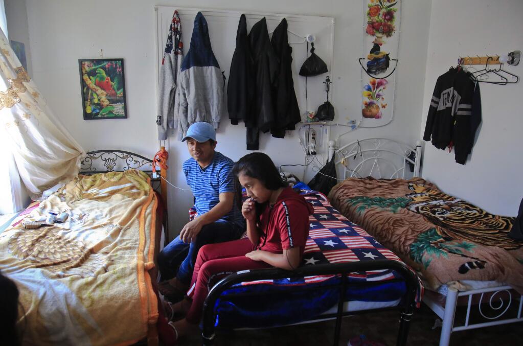 Manuela Adriana, 11, left, sit with her father Manuel Marcelino Tzah inside their apartment hours after her release from immigrant detention, Wednesday July 18, 2018, in Brooklyn borough of New York. The Guatemalan asylum seekers were separated May 15 after they crossed the U.S. border in Texas. (AP Photo/Bebeto Matthews)