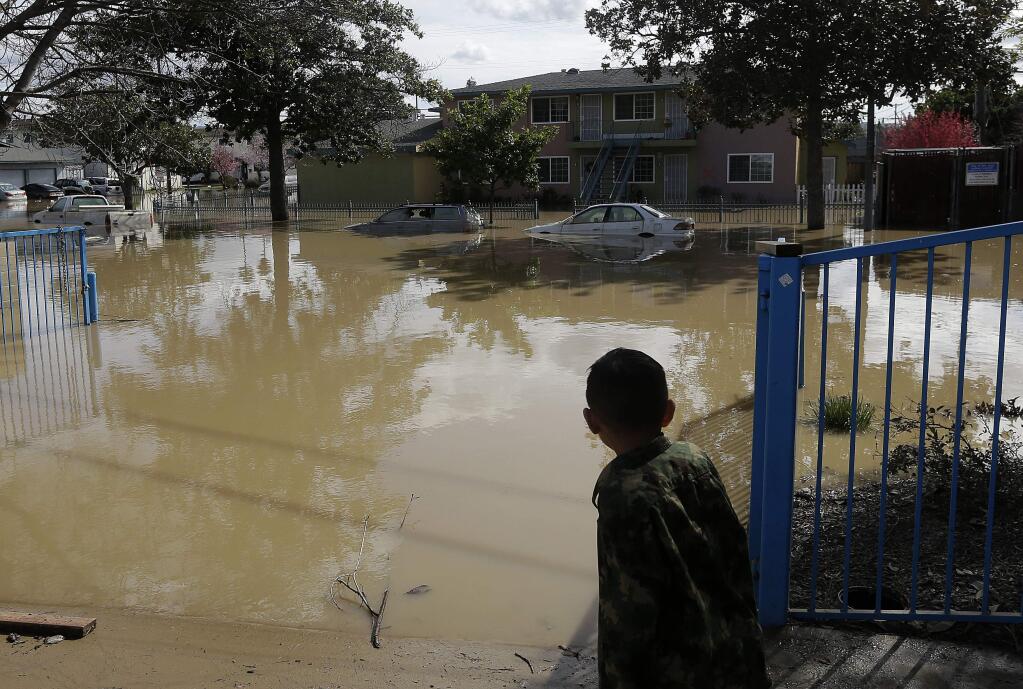 A boy looks onto flooded Nordale Avenue in San Jose, Calif., Wednesday, Feb. 22, 2017. Rising floodwaters sent thousands of residents fleeing inundated homes in San Jose and forced the shutdown of a major freeway Wednesday. (AP Photo/Jeff Chiu)