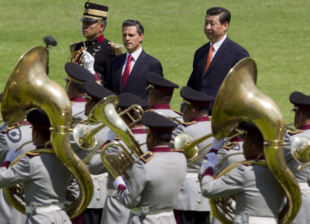 FILE - In this Tuesday, June 4, 2013 file photo, Chinese President Xi Jinping, top right, and his Mexican President Enrique Pena Nieto, top center, walk past a military band during a welcome ceremony at the Campo de Marte military field in Mexico City. Xi meets his American counterpart Barack Obama on Friday, June 7 and Saturday, June 8, following stops in the Caribbean and Latin America as the leader of a more confident China following a decade of explosive economic and trade growth. From Trinidad to Mexico City, Xi presented Beijing as an important partner for developing countries and a source of markets and finance, handing out nearly $4 billion in loans and promising to boost imports. (AP Photo/Eduardo Verdugo, File)