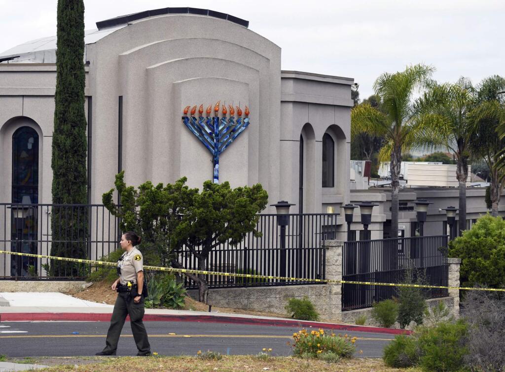FILE - In this April 28, 2019 file photo, a San Diego county sheriff's deputy stands in front of the Poway Chabad Synagogue in Poway, Calif. Federal officials announced Thursday, May 9, 2019, that they have filed 109 hate crime charges against John T. Earnest, accused of opening fire in the Southern California synagogue on April 27, the last day of Passover, a major Jewish holiday. (AP Photo/Denis Poroy, File)