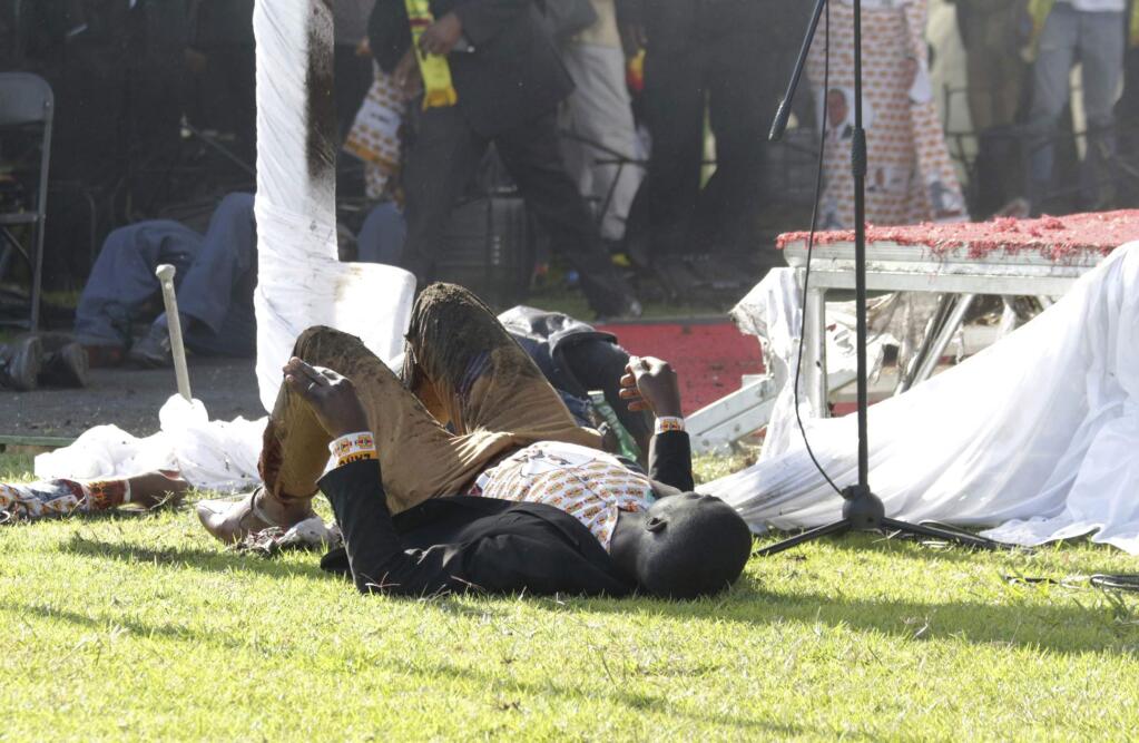 Injured people lay on the ground following an explosion at a Zanu pf rally in Bulawayo, Saturday, June, 23, 2018. An explosion rocked a stadium where Zimbabwe's president was addressing a campaign rally on Saturday, with state media calling it an assassination attempt but saying he was not hurt and was evacuated from the scene. Witnesses said several people were injured, including a vice president. (AP Photo)