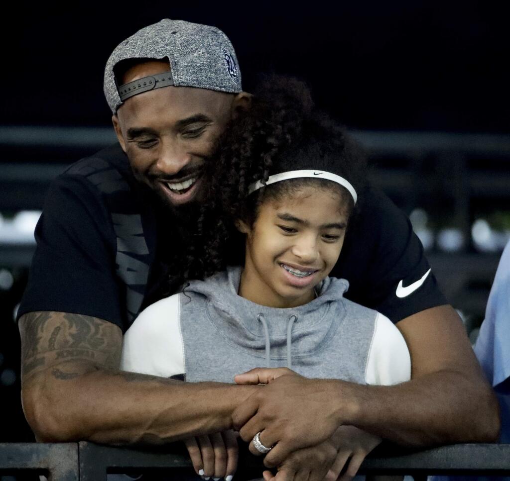 FILE - In this July 26, 2018 file photo former Los Angeles Laker Kobe Bryant and his daughter Gianna watch during the U.S. national championships swimming meet in Irvine, Calif. Bryant, the 18-time NBA All-Star who won five championships and became one of the greatest basketball players of his generation during a 20-year career with the Los Angeles Lakers, died in a helicopter crash Sunday, Jan. 26, 2020. Gianna also died in the crash. She was 13. (AP Photo/Chris Carlson)