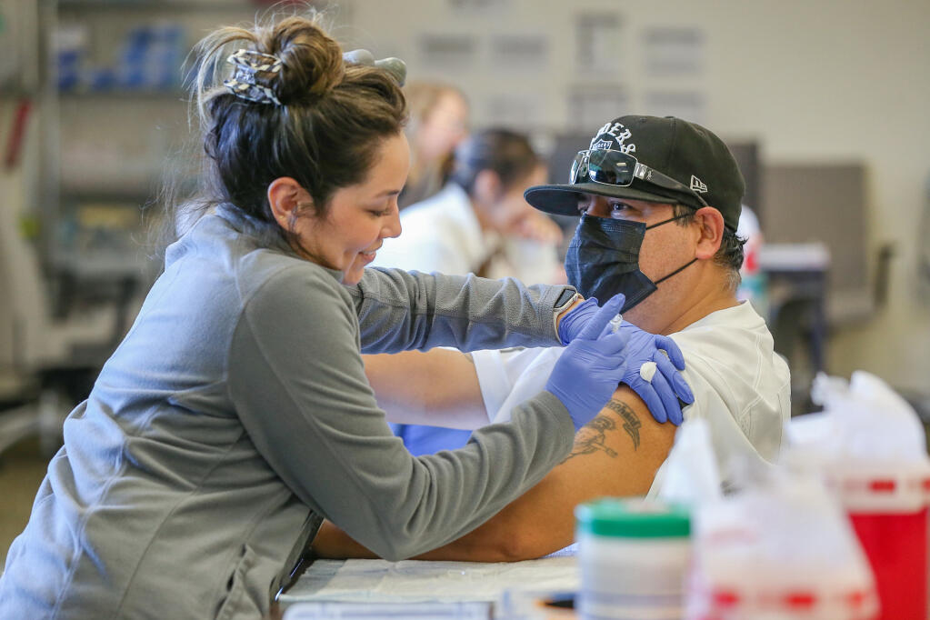 Medical assistant Gabriela Olvera, left, administers the Moderna Spikevax COVID-19 vaccine to Juan Paguini at the Sutter Pacific Medical Foundation Vaccine Clinic in Santa Rosa, Tuesday, Oct. 17, 2023. (Christopher Chung / The Press Democrat)