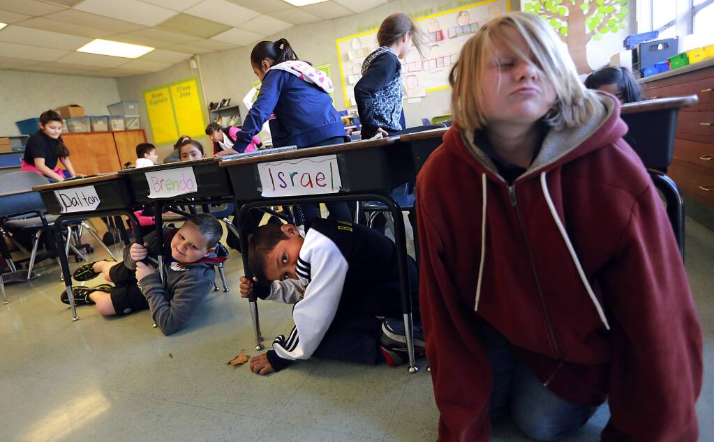 Bellevue Elementary School third graders Sarah McLaughlin, right, Israel Cruz and Dalton Jones crawl out from under their desks during an earthquake drill on Thursday, Oct. 16, 2014. (JOHN BURGESS/ PD)