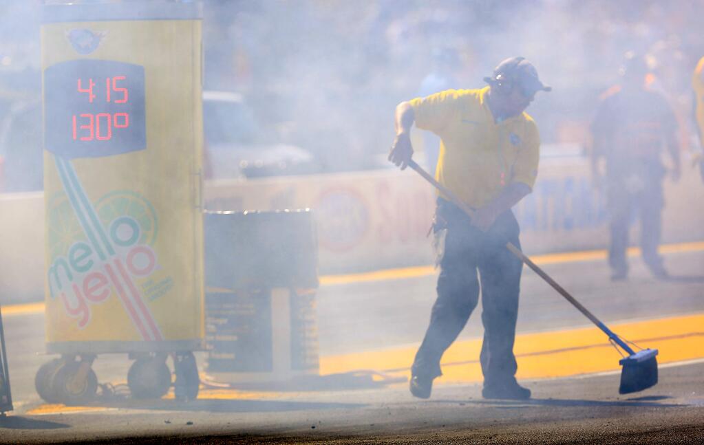 A worker sweeps the track area during a 2014 drag-racing event at Sonoma Raceway. (Kent Porter / The Press Democrat)