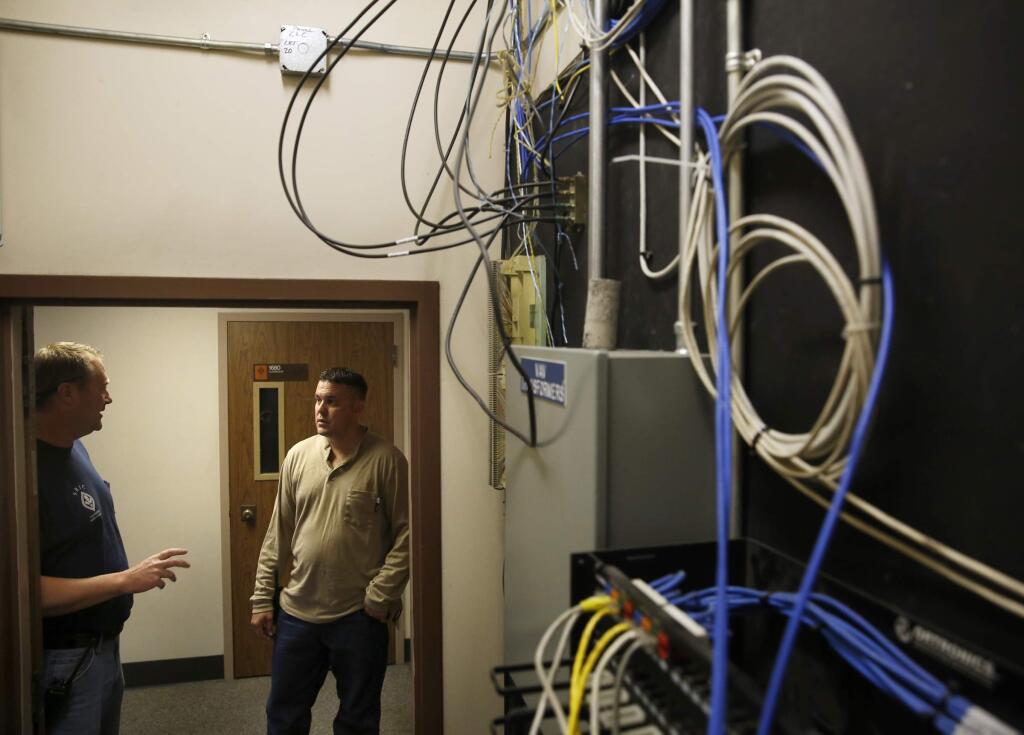 Campus electricians Erik Oden, left, and Scott Reese try to troubleshoot an electrical problem in Emeritus Hall at Santa Rosa Junior College in Santa Rosa, on Monday, August 4, 2014. (BETH SCHLANKER/ The Press Democrat)