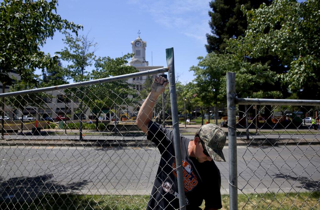 Shane Grunseth of Tri-City Fence Company assembled a chain link fence along the sidewalk as work got underway on the reunification project of Old Courthouse Square in Santa Rosa, on Monday, May 23, 2016. (BETH SCHLANKER/ The Press Democrat)