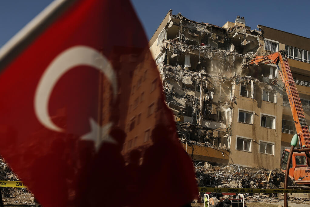 A worker in a bulldozer demolishes a building that was damaged at the Oct. 30 earthquake in Izmir, Turkey, Wednesday, Nov. 4, 2020. Search and rescue operations for survivors had been completed Wednesday at several buildings that fell in the coastal city. More that a hundred people were killed and more that a thousand people were injured. (AP Photo/Emrah Gurel)