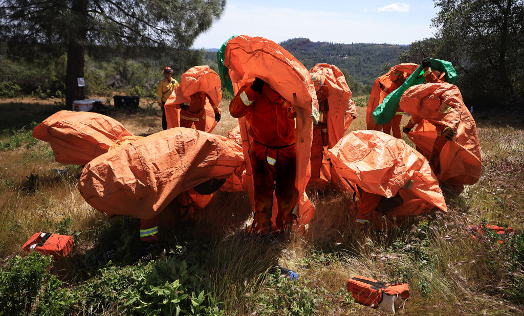 A California Department of Corrections inmate firefighting crew from Delta Conservation Camp located in Solano County, are timed as they use practice fire shelters in a scenario where they are being overrun by flames, as part a rigorous preparedness test, Wednesday, April 27, 2022, in Lake County. (Kent Porter / The Press Democrat)