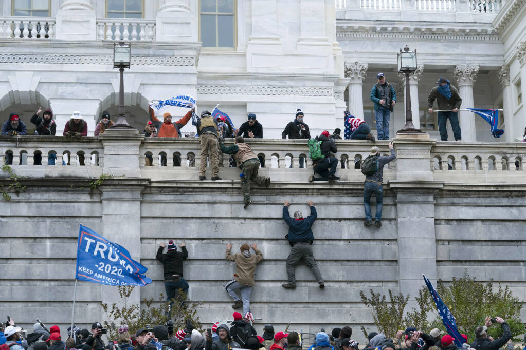Supporters of Donald Trump scale a wall at the U.S. Capitol during the Jan. 6 insurrection. (JOSE LUIS MAGANA / Associated Press)