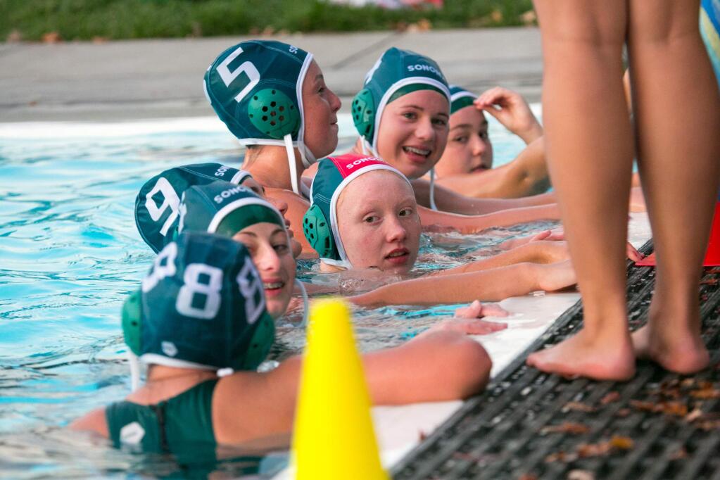 Goalie Molly Brown (red cap) and SVHS teammates gather between quarters at the Sonoma Aquatic Club pool. (Photo by Julie Vader/Special to the Index-Tribune)