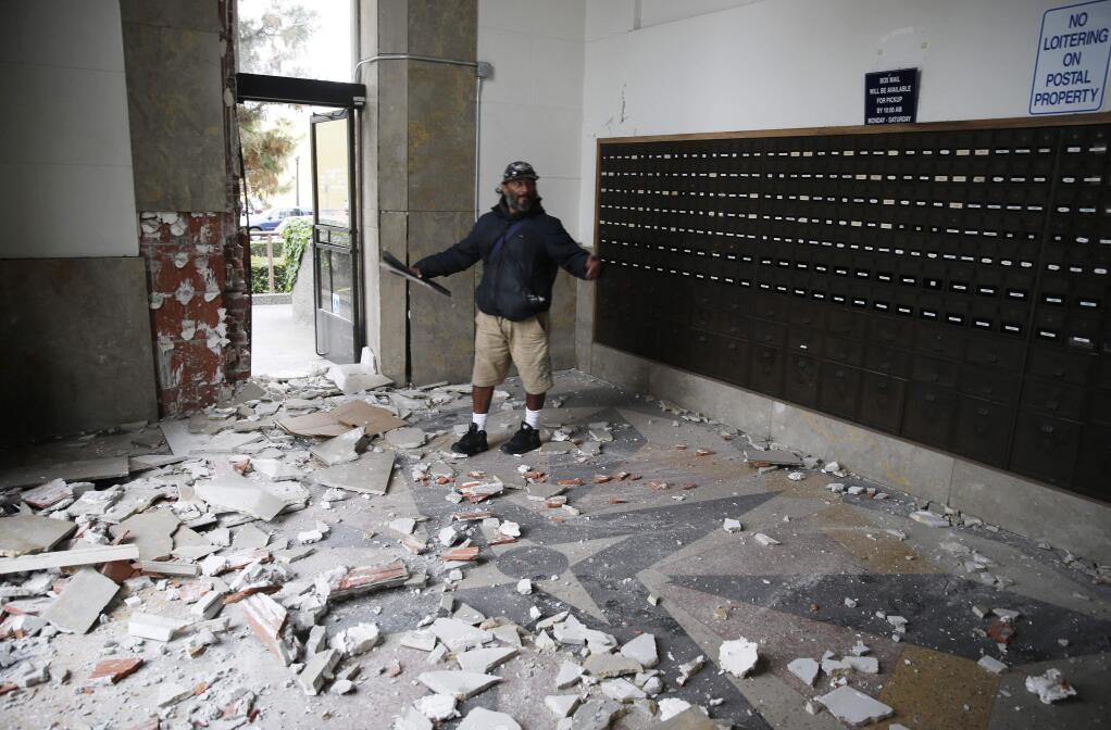 Jorge Sanchez looks over damage to the main post office following an earthquake Sunday, Aug. 24, 2014, in Napa. A large earthquake caused significant damage in California's northern Bay Area early Sunday, sending at least 90 people to a hospital, igniting fires, knocking out power to tens of thousands and sending residents running out of their homes in the darkness. (AP Photo/Eric Risberg)