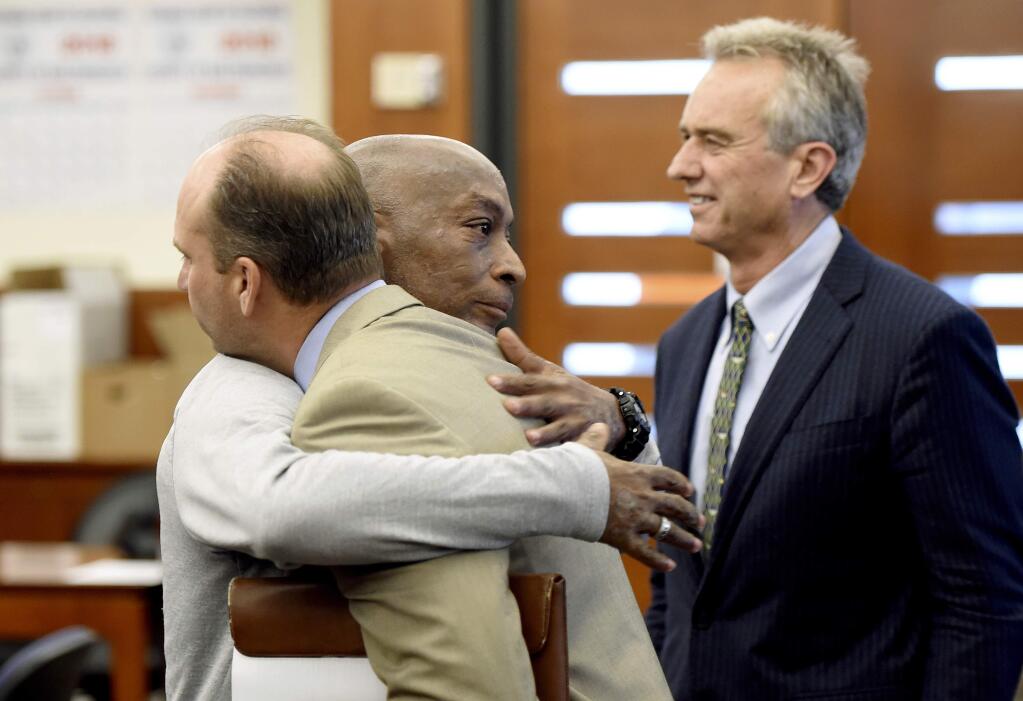 Dewayne Johnson, center, hugs one of his attorneys, next to lawyer and member of his legal team Robert F Kennedy Jr., right, after the verdict was read in his case against Monsanto at the Superior Court of California in San Francisco on Friday, Aug. 10, 2018. A San Francisco jury on Friday ordered agribusiness giant Monsanto to pay $289 million to the former school groundskeeper dying of cancer, saying the company's popular Roundup weed killer contributed to his disease. (Josh Edelson/Pool Photo via AP)