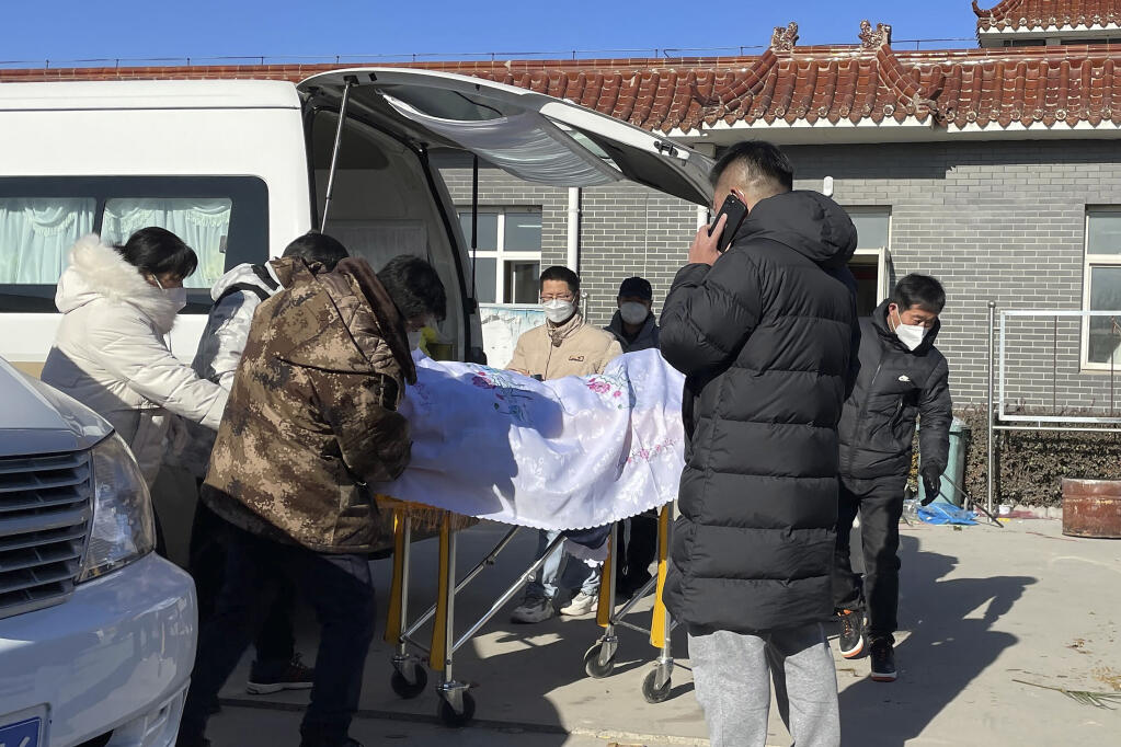 Liang from Beijing, center looks on as his 82-year-old grandmother is brought in a casket to the Gaobeidian Funeral Home in northern China's Hebei province, Thursday, Dec. 22, 2022. Liang's grandmother had been unvaccinated when she came down with coronavirus symptoms, and had spent her final days hooked to a respirator in a Beijing ICU. (AP Photo)