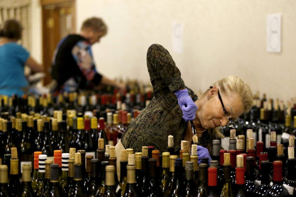 Ginger Kuhn opens bottles for tasting by the judges during the North Coast Wine Challenge at the Hilton Sonoma Wine Country Hotel in Santa Rosa, on April 12. (BETH SCHLANKER/ The Press Democrat)