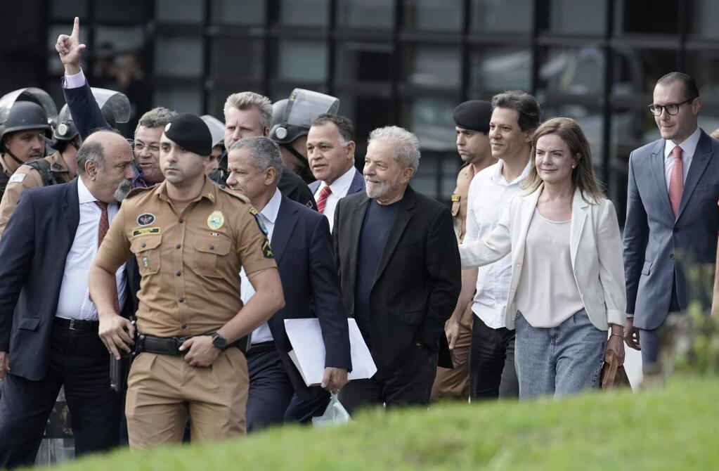 Brazil's former President Luiz Inacio Lula da Silva, center, exits the the Federal Police headquarters where he was imprisoned on corruption charges in Curitiba, Brazil, Friday, Nov. 8, 2019. Da Silva walked out of prison less than a day after the Supreme Court ruled that a person can be imprisoned only after all the appeals have been exhausted. (AP Photo/Leo Correa)