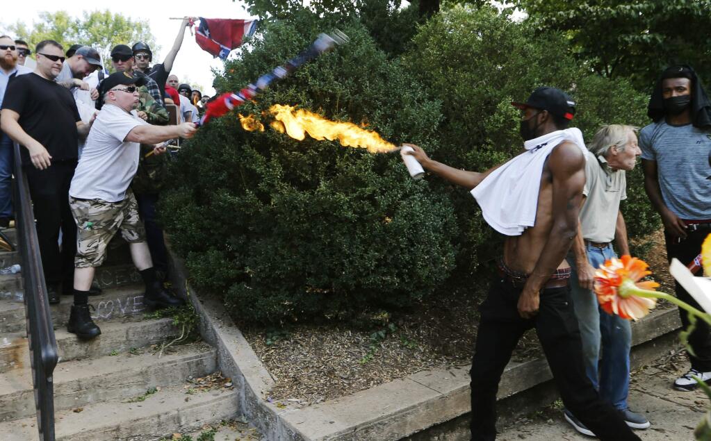 A counter demonstrator uses a lighted spray can against a white nationalist demonstrator at the entrance to Lee Park in Charlottesville, Va., Saturday, Aug. 12, 2017. Gov. Terry McAuliffe declared a state of emergency and police dressed in riot gear ordered people to disperse after chaotic violent clashes between white nationalists and counter protestors. (AP Photo/Steve Helber)