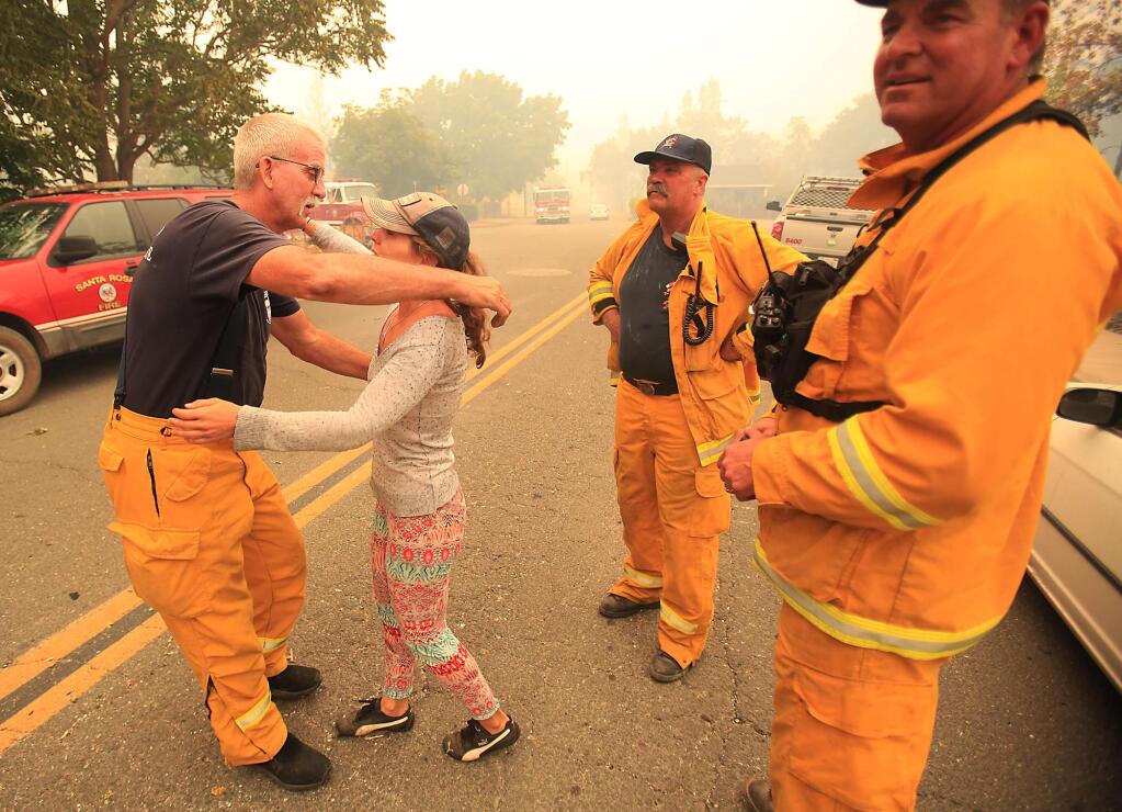 Monte Rio Fire Chief Steve Baxman gets a hug from a resident who's home was saved by a strike team from Sonoma County which included Santa Rosa city BC Bill Shubin, right and Roger Wheeler of Sonoma Valley Fire, Sunday Sept. 13, 2015. (Kent Porter / Press Democrat) 2015