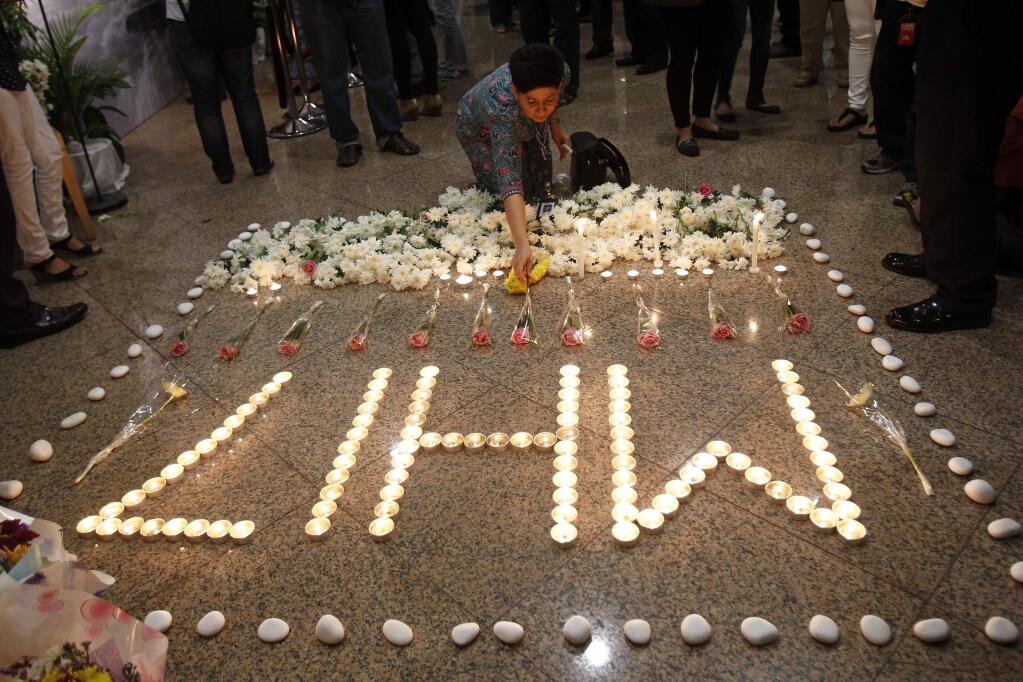 FILE - In this Friday, July 25, 2014 file photo, a Malaysia Airlines crew member places a flower next to candles forming the letters MH17 after a multi-faith prayers for the victims of the downed Malaysia Airlines Flight 17 at Malaysia Airlines Academy in Kelana Jaya, near Kuala Lumpur, Malaysia. The Dutch Safety Board is publishing its final report Tuesday, Oct. 13, 2015 into what caused Malaysia Airlines Flight 17 to break up high over Eastern Ukraine last year, killing all 298 people on board. (AP Photo/Lai Seng Sin, File)