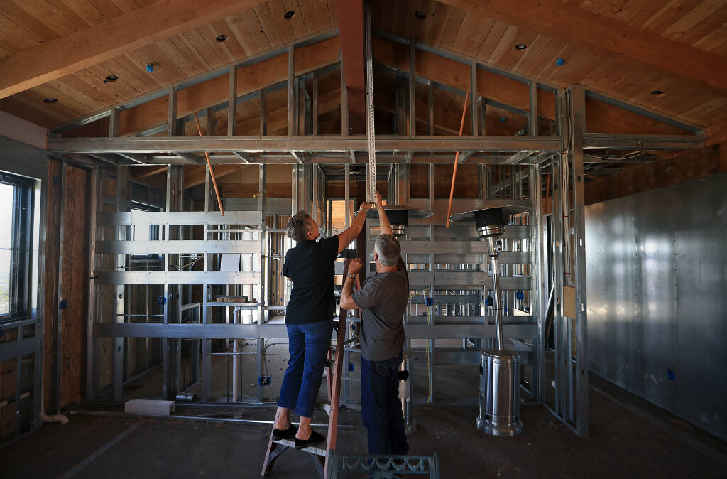 Lisa Yoshida, left, and Jim Hunt imeasure the distance from the ceiling to the subfloor n their partially rebuilt home in Foothill Ranch, Friday, July 8, 2022.  The couple were in the direct path of the 2017 Tubbs Fire, and like so many others, lost their home during the first hours of the firestorm. (Kent Porter/The Press Democrat)