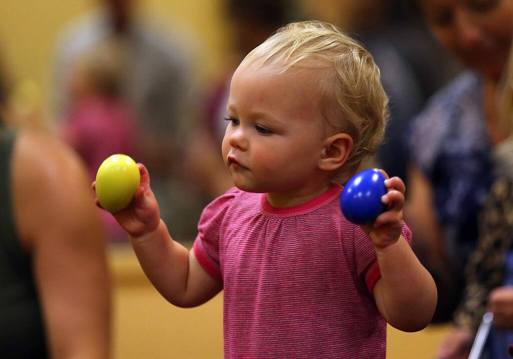 Stella Pile, 15 months, uses the two handed egg shaker method at the Music Together class at Ellington Hall in Santa Rosa. (JOHN BURGESS / The Press Democrat)