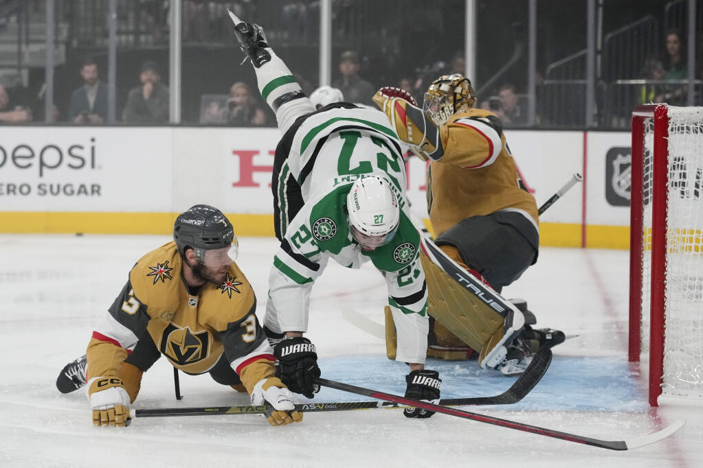 Dallas Stars left wing Mason Marchment (27) falls over Vegas Golden Knights defenseman Brayden McNabb (3) during the first period of Game 1 of the NHL hockey Stanley Cup Western Conference finals Friday, May 19, 2023, in Las Vegas. (AP Photo/John Locher)