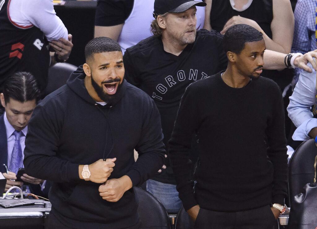 Rapper Drake, front left, yells courtside as the Toronto Raptors take on the Golden State Warriors during the first half of Game 2 of basketball's NBA Finals, Sunday, June 2, 2019, in Toronto. (Nathan Denette/The Canadian Press via AP)