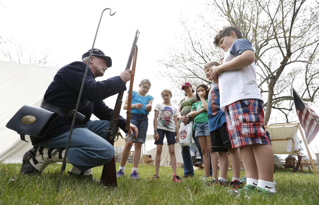 Historical interpreter Joe McShane, of Kittanning Pa., shows Elijah Callahan, right, of Lynchburg, Va., a Civil War era replica rifle during preparations for the 150th anniversary of the surrender of the Army of Northern Virginia to Union forces at Appomattox Court House, Wednesday, April 8, 2015, in Appomattox, Va. (AP Photo/Steve Helber)