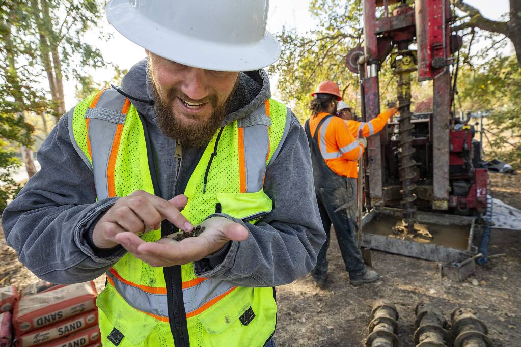 Bryce Russell, with the California Department of Water Resources, checks a sample of soil collected from 20 feet underground as a crew digs a well on Hardies Ln. near Santa Rosa creek on Thursday. (photo by John Burgess/The Press Democrat)
